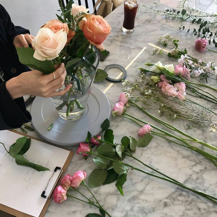 Cắm hoa tươi: Người đang sắp xếp và cắm những bông hoa hồng tươi vào bình thủy tinh.
